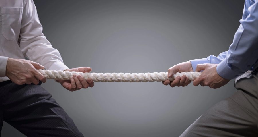Two businesspeople pulling opposite ends of a rope