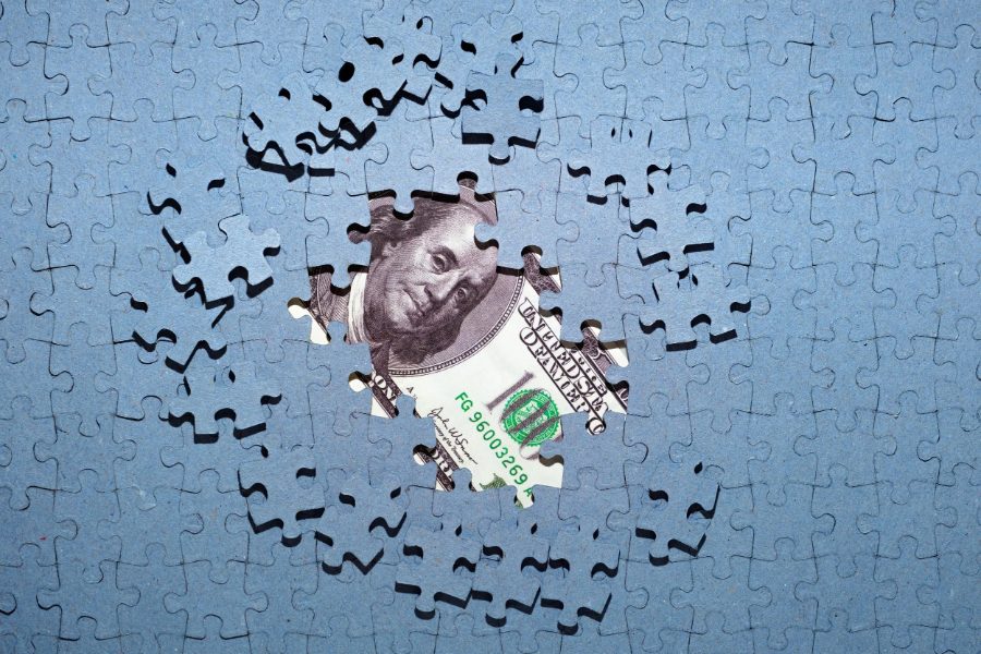 Jigsaw puzzle with a missing piece revealing money underneath